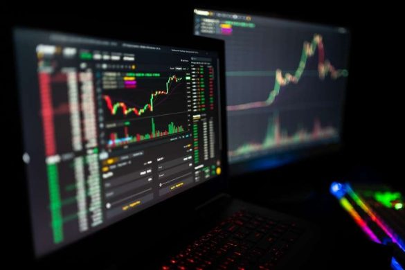 Ordinateur portable affichant des données et un graphique crypto dans une pièce sombre.