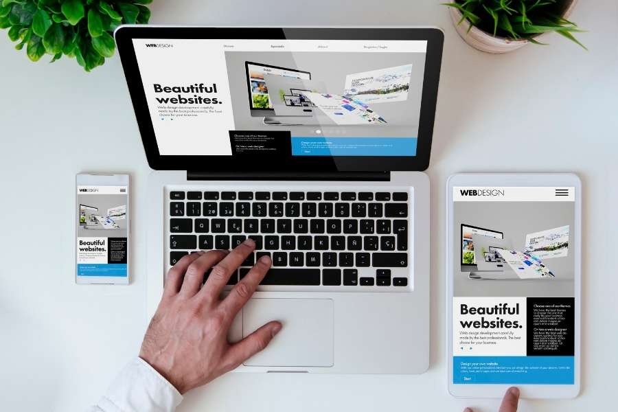Vue du dessus d'un ordinateur portable, d'une tablette et d'un smartphone affichant le même site web adaptatif.