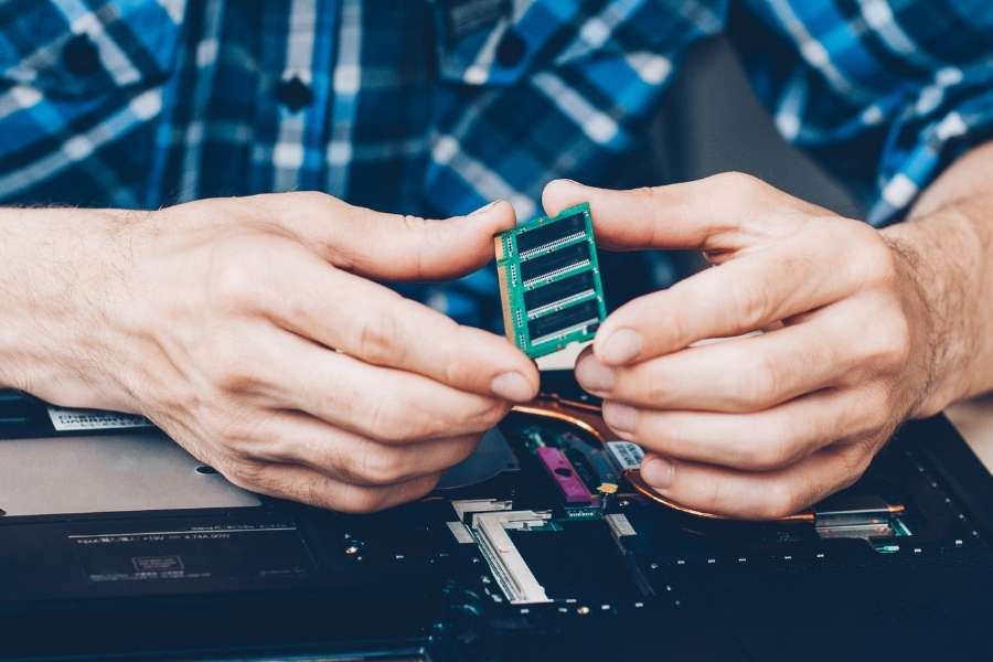 Un prestataire informatique installe une barrette de mémoire RAM sur un ordinateur portable.