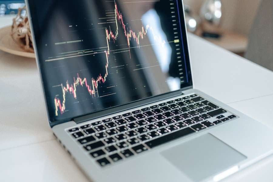 Un écran d'ordinateur portable affiche des graphiques financiers complexes illustrant l'analyse de marché liée au staking de cryptomonnaies.