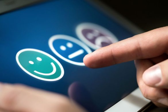 Un utilisateur sélectionne un émoji souriant sur une tablette tactile pour donner son avis sur son expérience client.