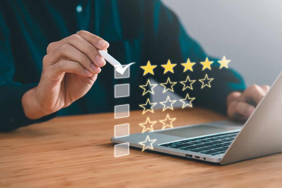 Une personne évalue un service avec cinq étoiles sur un ordinateur portable pour mesurer l'expérience client.